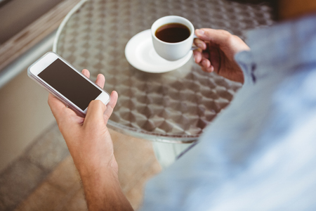 Close up view of businessman texting while holding cup of coffeeの写真素材
