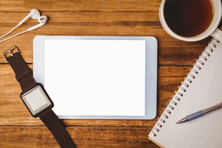 Swatch on tablet next to cup of coffee on wooden tableの写真素材