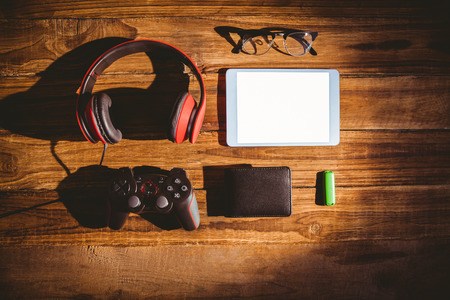 Tablet and USB key next to glasses wallet and joystick on wooden tableの写真素材