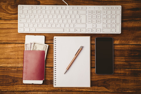 Pen on notepad passport smartphone and keyboard on wooden table