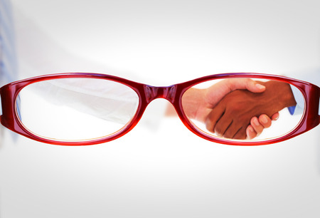 Two businessmen shaking hands in office against glassesの写真素材