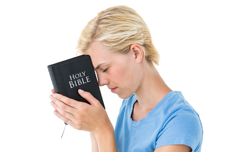 Pretty blonde woman holding bible on white background