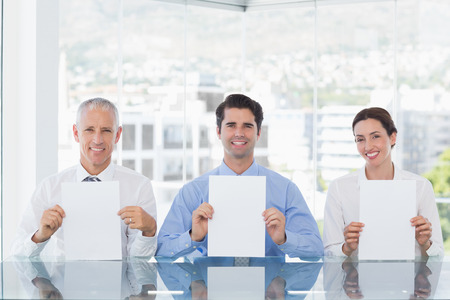 Smiling business team showing paper in the officeの写真素材