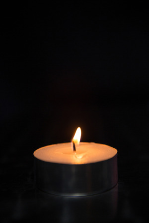 Blazing candle on black backgroundの写真素材