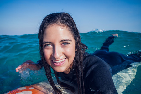 woman in wetsuit with a surfboard on a sunny day at the beachの写真素材