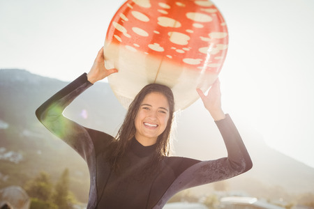 woman in wetsuit with a surfboard on a sunny day at the beachの写真素材