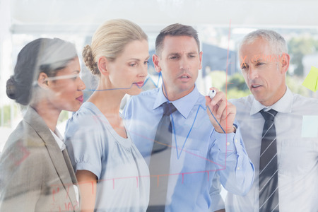Businessman drawing graph on the glass in the officeの写真素材