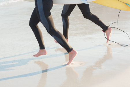 Two men in wetsuits with a surfboard on a sunny day at the beachの写真素材