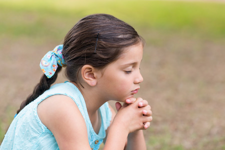 Little girl saying his prayers on a sunny dayの写真素材