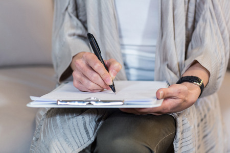 Psychologist sitting on the couch and taking notes in the officeの写真素材