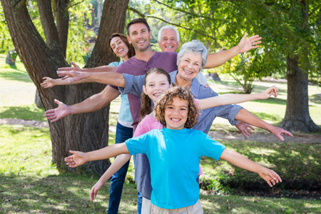 Extended family smiling in the park on a sunny dayの写真素材