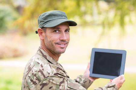 Soldier looking at tablet pc in park on a sunny dayの写真素材