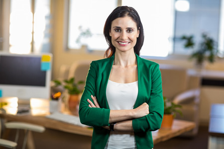 Smiling brunette standing arms crossed in the officeの写真素材