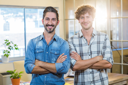 Smiling team standing arms crossed in the officeの写真素材