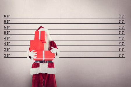 Santa covers his face with presents against mug shot background