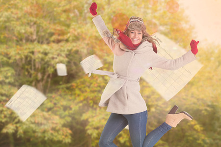 Happy blonde in winter clothes posing against peaceful autumn scene in forestの写真素材