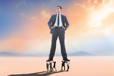 Business people supporting boss against desert landscapeの写真素材