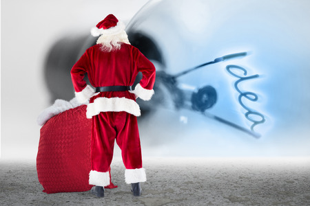 Santa with sack of gifts against idea filament in light bulbの写真素材