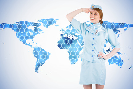 Pretty air hostess looking up against background with hexagons and world mapの写真素材