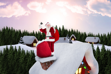 Santa on cottage roof  against snow covered village in forestの写真素材