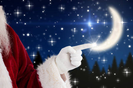 Santa Claus points at something against twinkling starsの写真素材