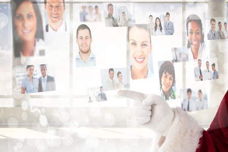 Santa Claus points at something against lights twinkling in room with windowsの写真素材