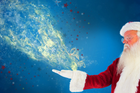 Santa shows something to camera against blue backgroundの写真素材