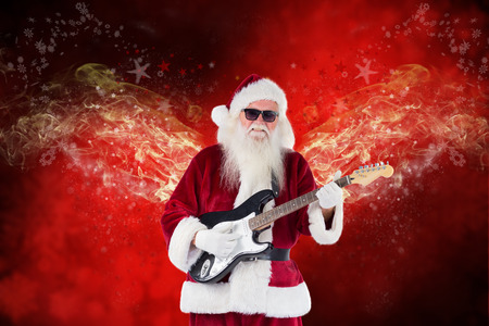 Santa Claus plays guitar with sunglasses against blurred snowflakes on red planksの写真素材