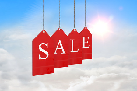 Red sale tags against blue sky with white cloudsの写真素材
