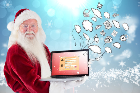 Santa Claus presents a laptop against blue design with white snowflakesの写真素材
