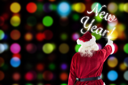 Santa Claus points at something against colourful circles on black backgroundの写真素材