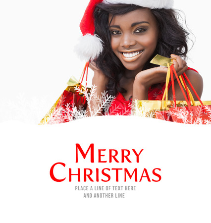 Festive woman standing looking while holding bags  against merry christmasの写真素材
