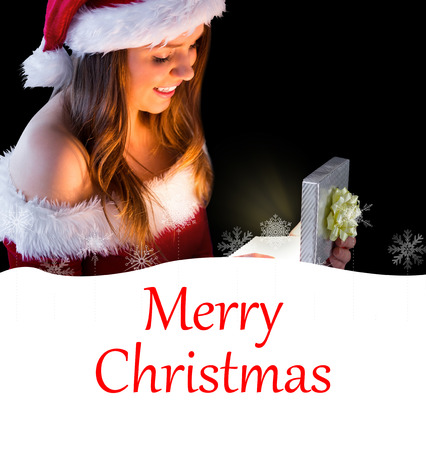 Pretty brunette in santa outfit opening gift against merry christmasの写真素材
