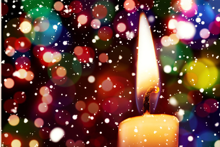 Snow falling against candle burning against festive backgroundの写真素材
