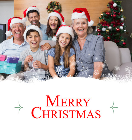Extended family in Christmas hats with gift boxes in living room against borderの写真素材