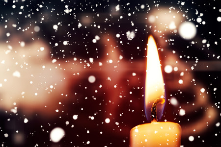 Snow falling against candle burning against festive backgroundの写真素材