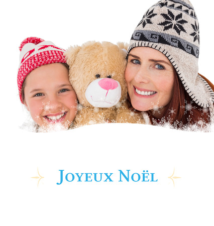 Mother and daughter holding teddy bear against Christmas greeting cardの写真素材
