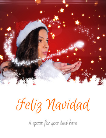 pretty girl in santa outfit blowing against feliz navidadの写真素材