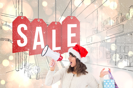 Festive brunette holding megaphone and bags against white glowing dots on greyの写真素材