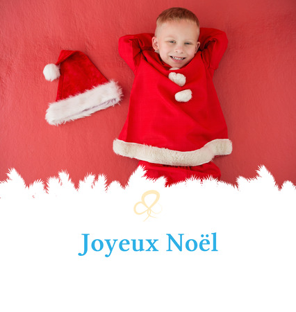 Little boy in santa costume against Christmas greeting cardの写真素材