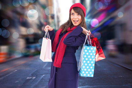 Young woman in winter clothes posing with shopping bags against blurry new york streetの写真素材