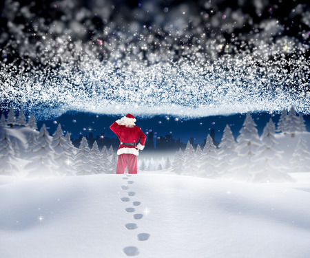 Santa walking in the snow against bright stars of energy over landscapeの写真素材