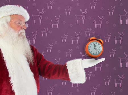 Santa shows something to camera against purple reindeer patternの写真素材