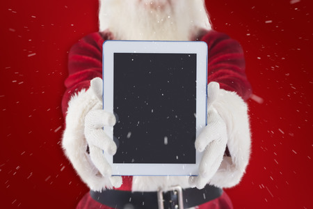 Santa presents a tablet PC against red backgroundの写真素材