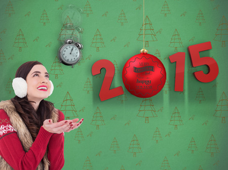Brunette in winter clothes with hands out against green christmas tree pattern