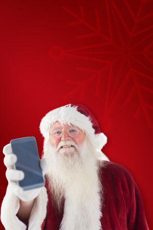 Santa Claus shows a smartphone against red backgroundの写真素材