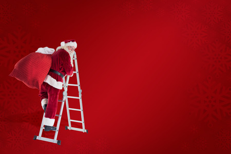 Santa steps up a ladder against red backgroundの写真素材