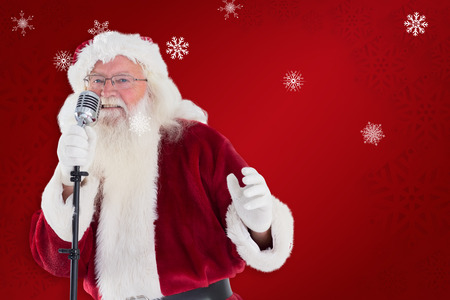 Santa Claus is singing Christmas songs against red snowflake backgroundの写真素材