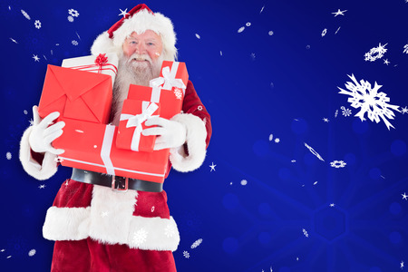 Santa carries a few presents against blue snowflake backgroundの写真素材