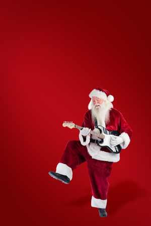 Santa Claus has fun with a guitar against red backgroundの写真素材